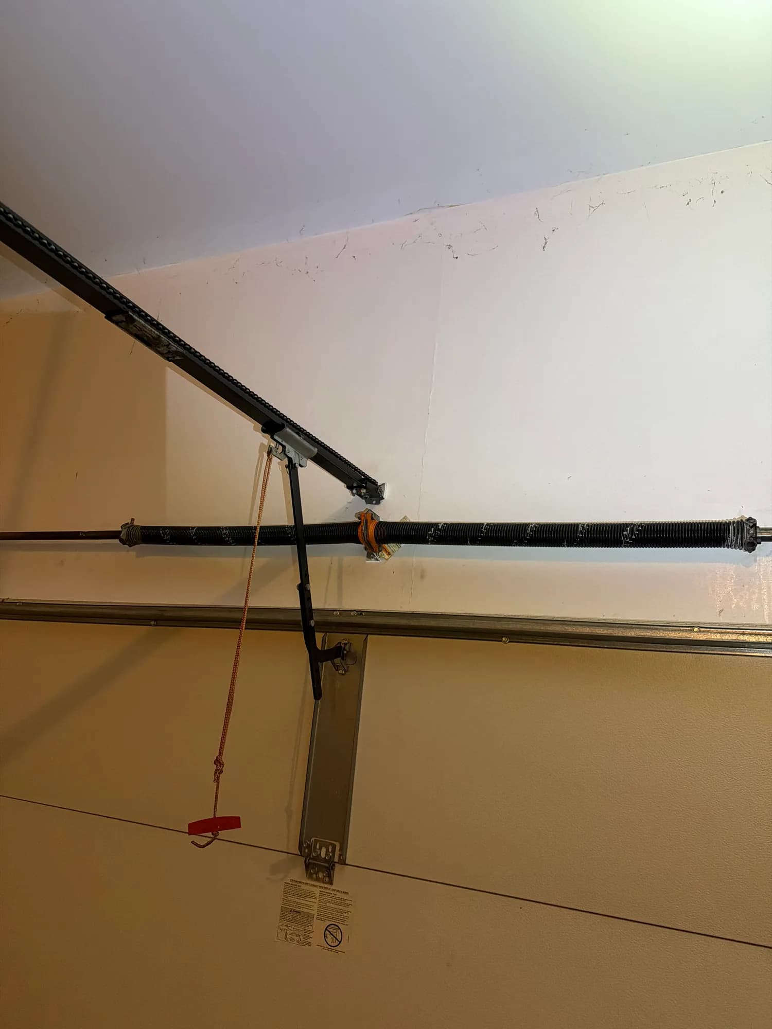 Garage door emergency release handle hanging from the opener rail