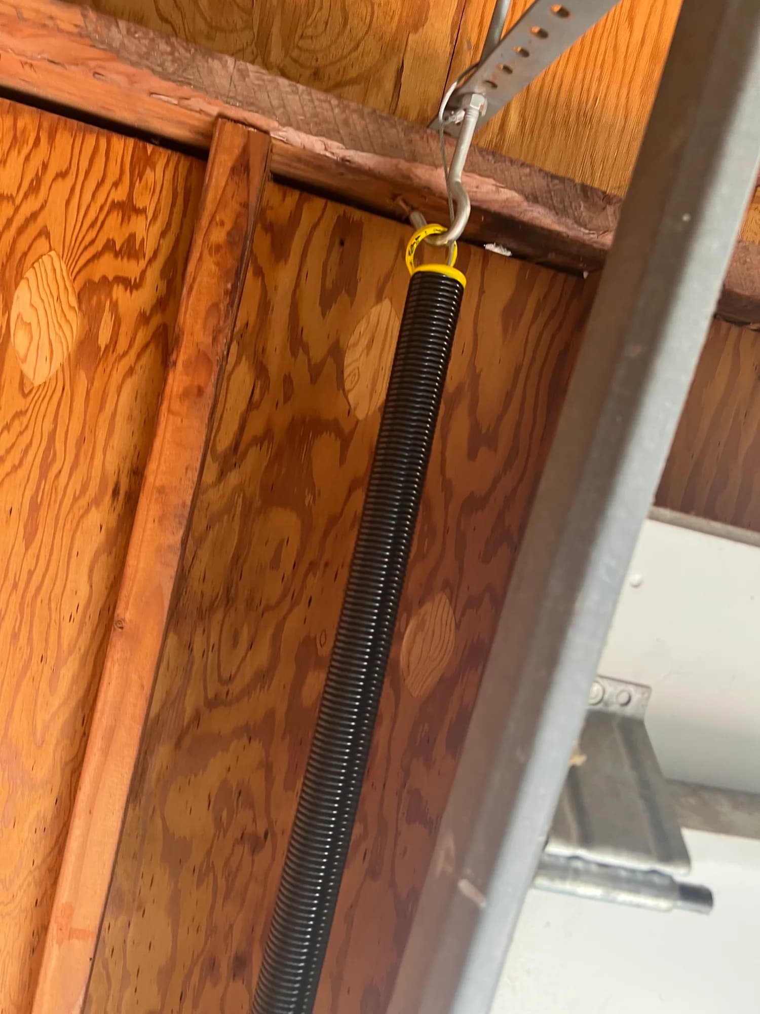 Black extension spring along a garage door track
