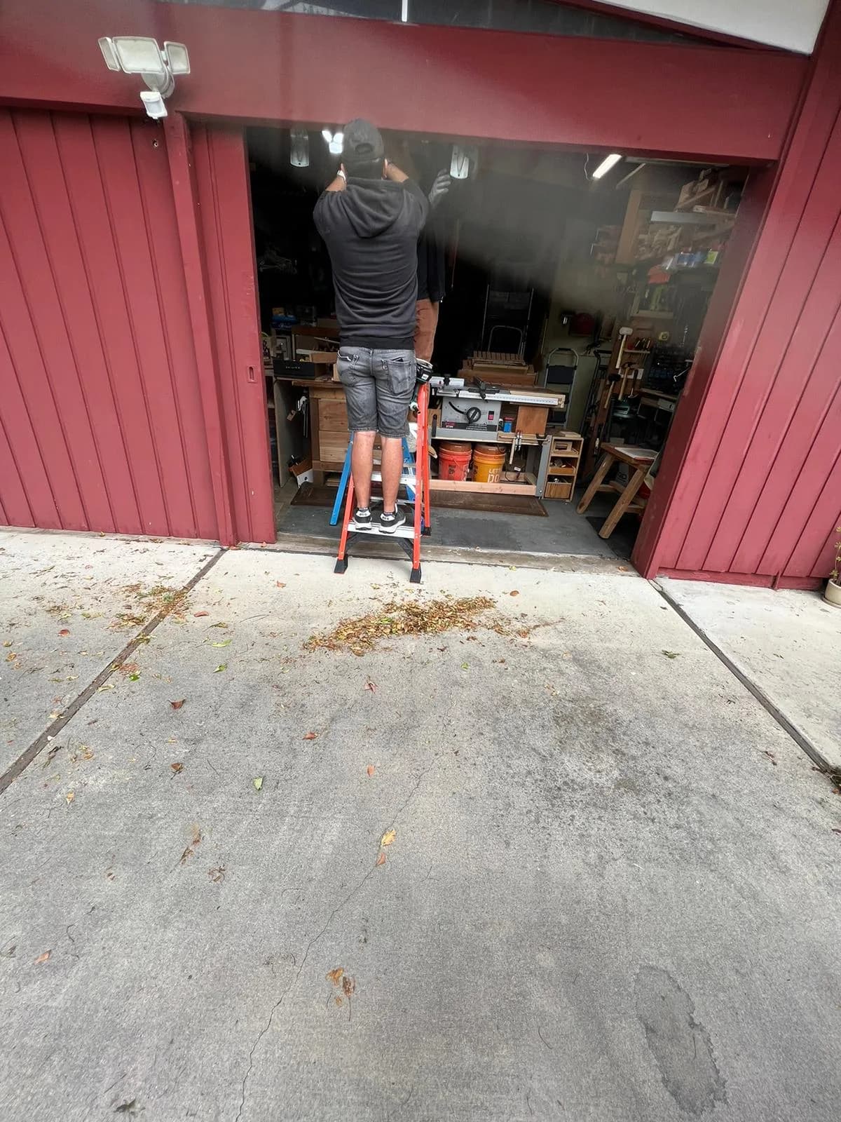 WeDo technician on a ladder repairing a garage door